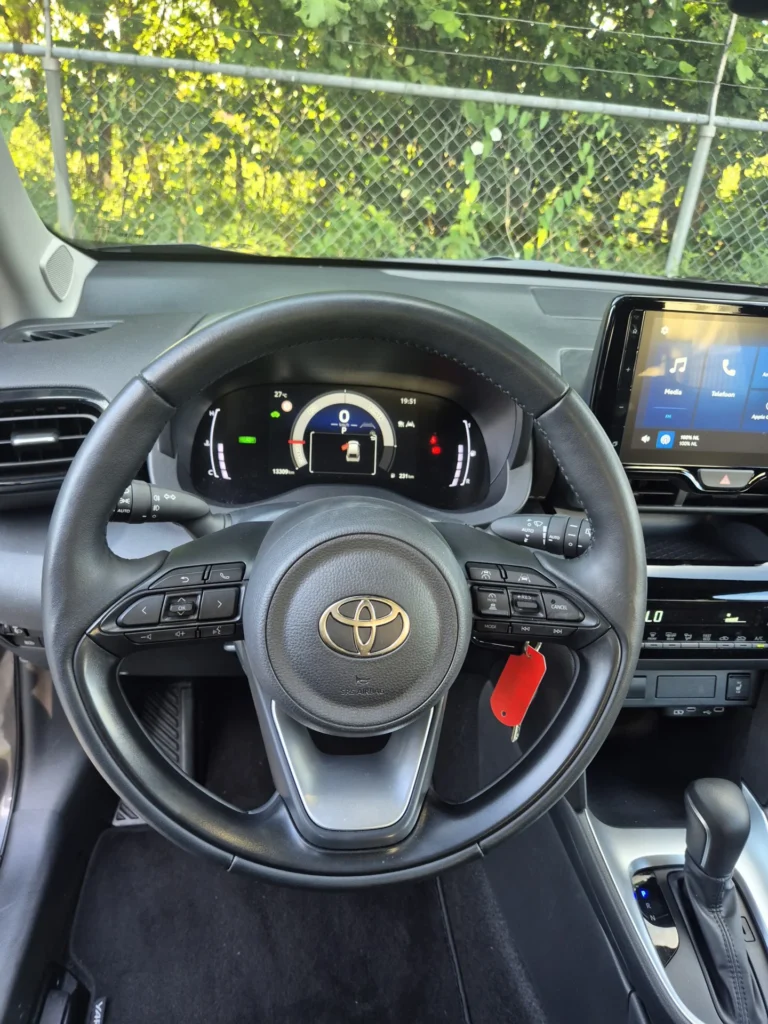 Stuurwiel en dashboard van een auto met scherm en snelheidsmeter.