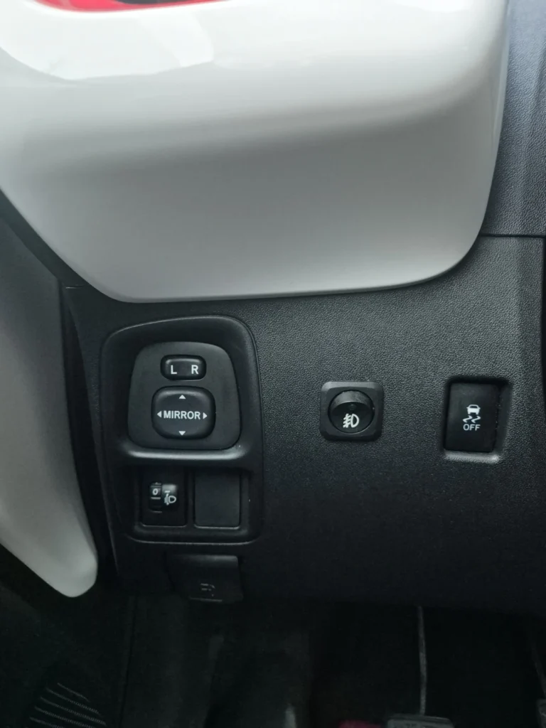 Knoppen op een autodashboard voor spiegels en verlichting.