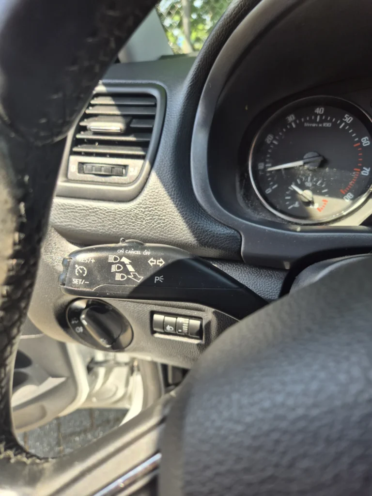 Close-up van een auto dashboard met snelheidsmeter en stuurbediening.