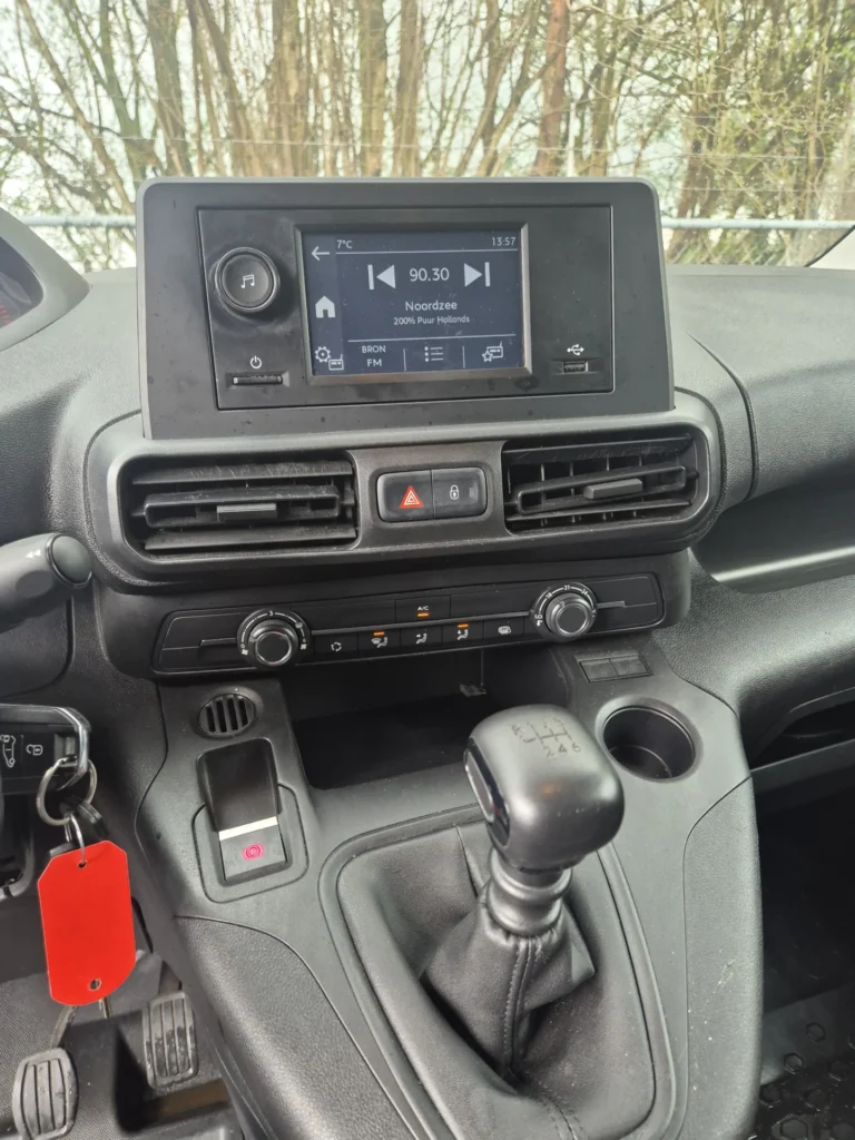 Dashboard met radio en versnellingspook in een auto.