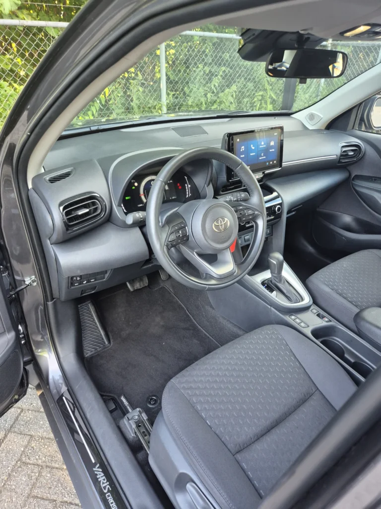 Stuur en dashboard van een auto met scherm en stoelen.