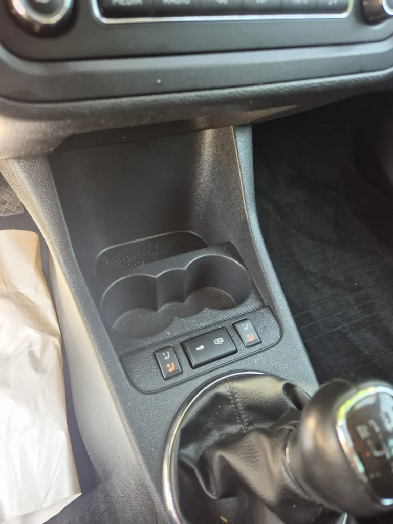 Middenconsole van een auto met schakelpook en knoppen.