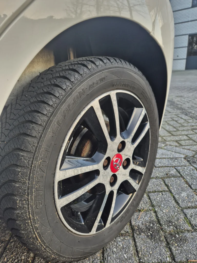 Autoband met zwarte en zilveren velg op bestrating.