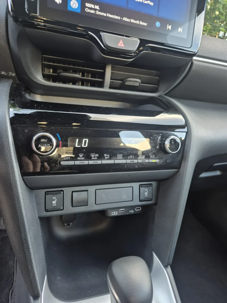 Dashboard met klimaatregeling en versnellingspook in een auto.