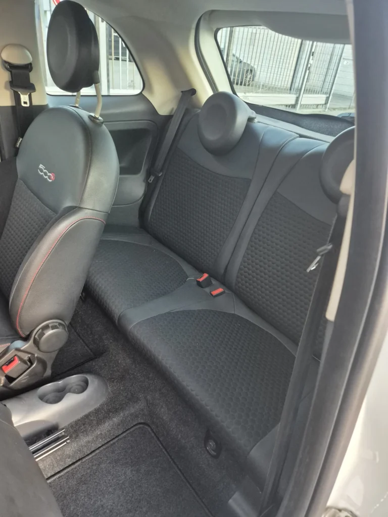 Achterbank en voorstoel van een compacte auto met zwart stoffen bekleding.