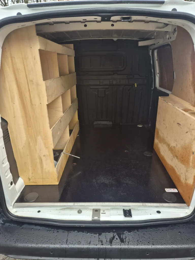 Interieur van een bestelwagen met houten rekken.