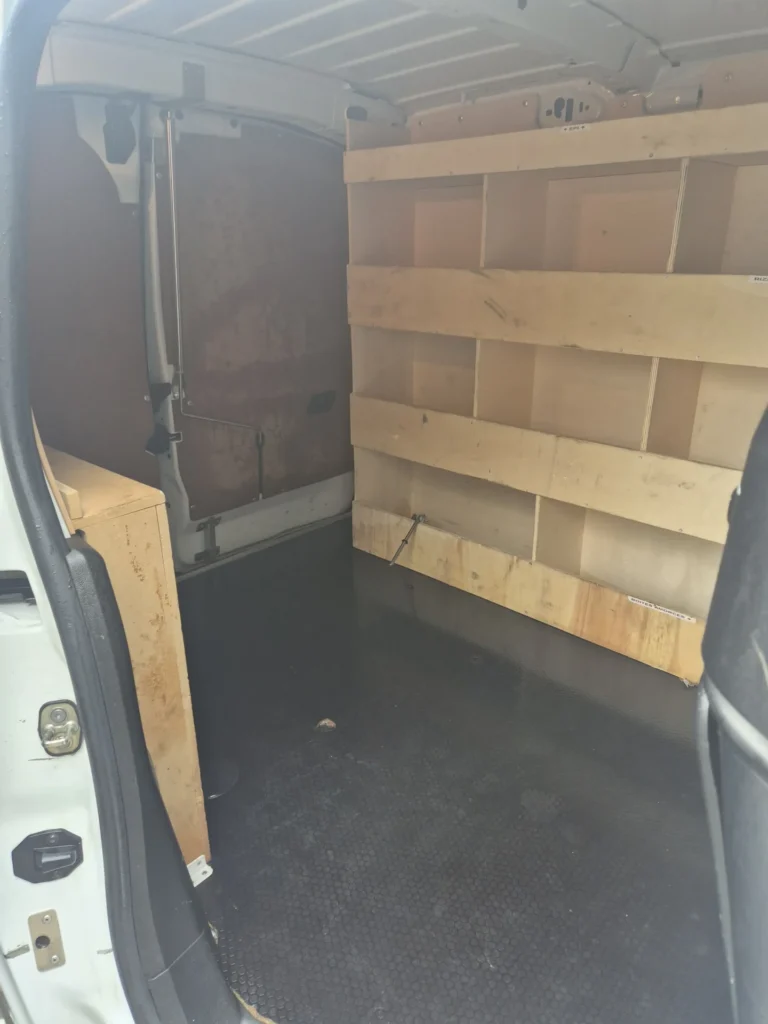 Interieur van een lege bestelwagen met houten panelen.