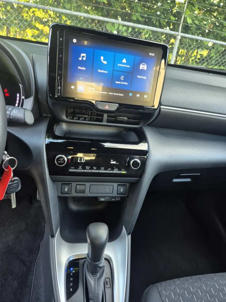 Dashboard en middenconsole van een auto met touchscreen en versnellingspook.