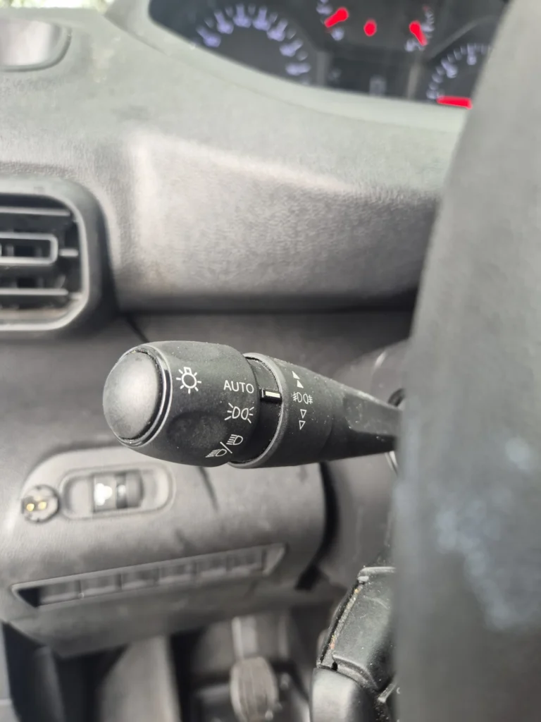 Stuurkolom met een lichtschakelaar en dashboard in een auto.