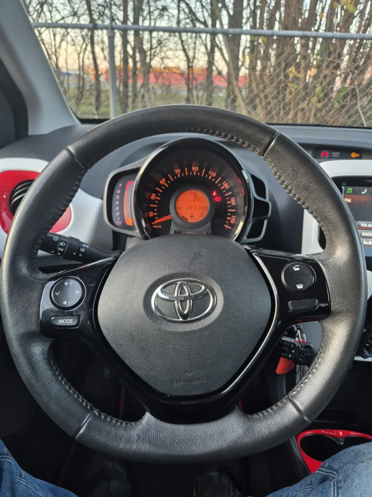 Stuurwiel met logo en dashboard met snelheidsmeter.
