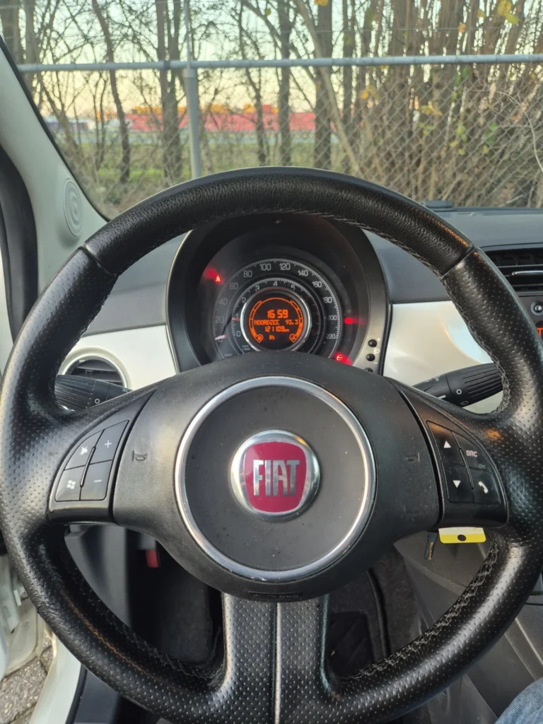 Stuurwiel van een Fiat met dashboard op de achtergrond.