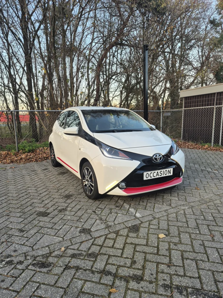 Witte Toyota Aygo met het bord 'Occasion' op een parkeerplaats.